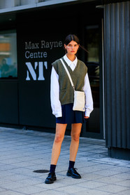school girl look, white shirt, oversize shirt, knitwear, sleeveless pullover, kaki pullover, man style pullover, porter bag, crossbody bag, black and white bag, square shape bag, navy blue skirt, pleated skirt, black socks, doc marteens shoes, laced shoes, black leather shoes, long sleeves shirt, oversize sleeves, hoop earrings, golden earrings, fashion week, frenchystyle, FW, jonathan paciullo, street style, vertical, full length