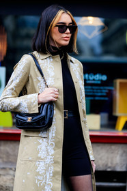 brittany xavier, black top, black sunglasses, black shorts, black tights, black leather bag, shoulder bag, chanel bag, black leather belt, tight shorts, belted top, turtleneck top, bottega veneta sunglasses, beige trench coat, white trench coat, floral embroidered trench coat, golden rings, diamond ring, multi rings, fashion week, frenchystyle, FW, jonathan paciullo, street style, PFW, PARIS, vertical, atmosphere details, detail