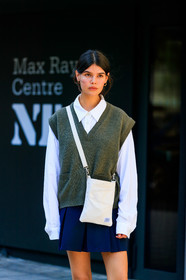 school girl look, white shirt, oversize shirt, knitwear, sleeveless pullover, kaki pullover, man style pullover, porter bag, crossbody bag, black and white bag, square shape bag, navy blue skirt, pleated skirt, black socks, doc marteens shoes, laced shoes, black leather shoes, long sleeves shirt, oversize sleeves, hoop earrings, golden earrings, fashion week, frenchystyle, FW, jonathan paciullo, street style, vertical, detail, atmosphere details